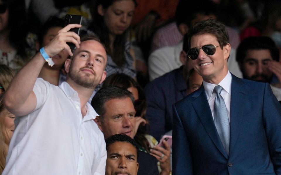 Tom Cruise (right) leans in for a selfie with a fan in the crowd at the men's singles final at Wimbledon on July 11, 2021.