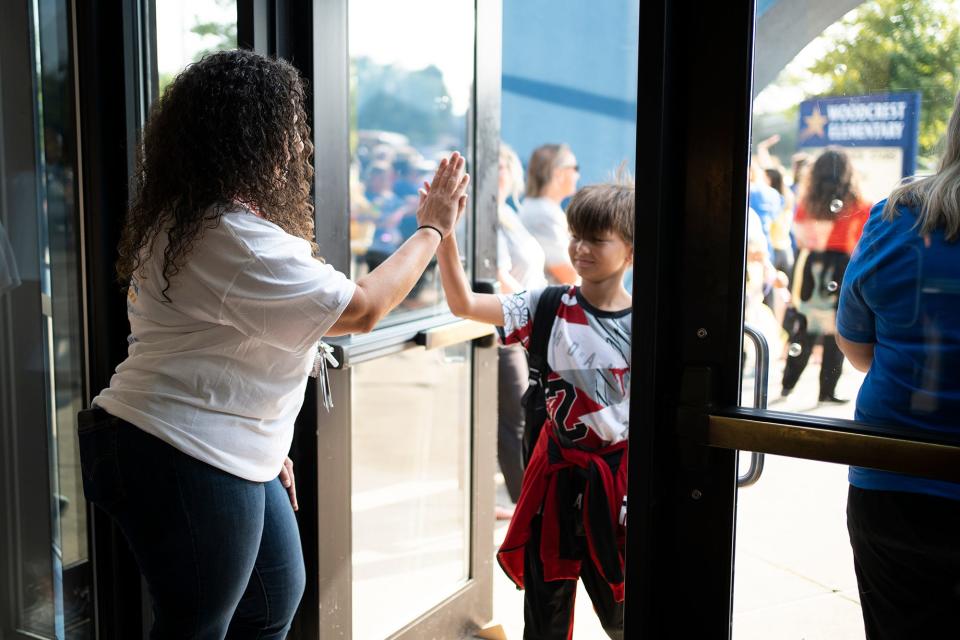 Third grade teacher Lirea Turner high-fives students as they arrive Wednesday at Woodcrest Elementary School for the first day of classes.