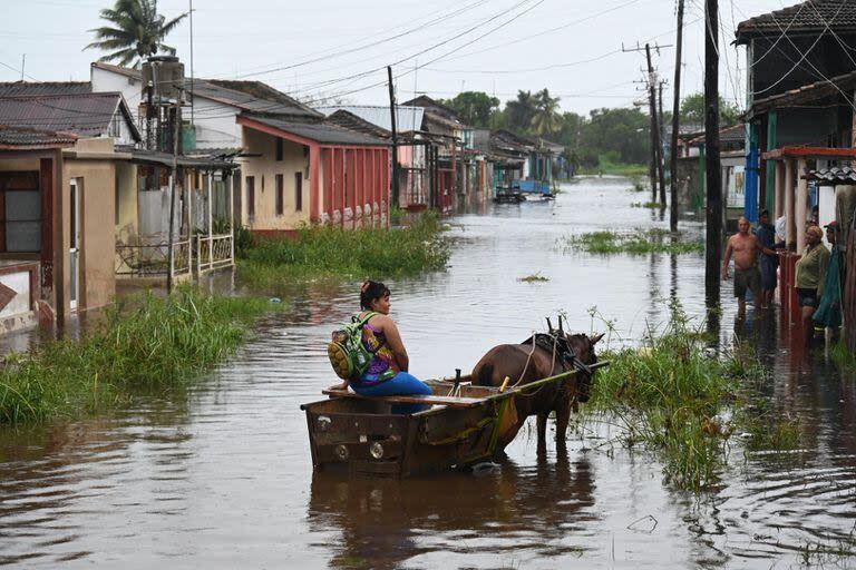 Una mujer viaja en un carruaje tirado por caballos por una calle inundada en Batabano, provincia de Mayabeque, Cuba, durante el paso de la tormenta tropical Idalia. La tormenta tropical Idalia se fortaleció hasta convertirse en huracán este martes y los meteorólogos pronostican que se volverá 