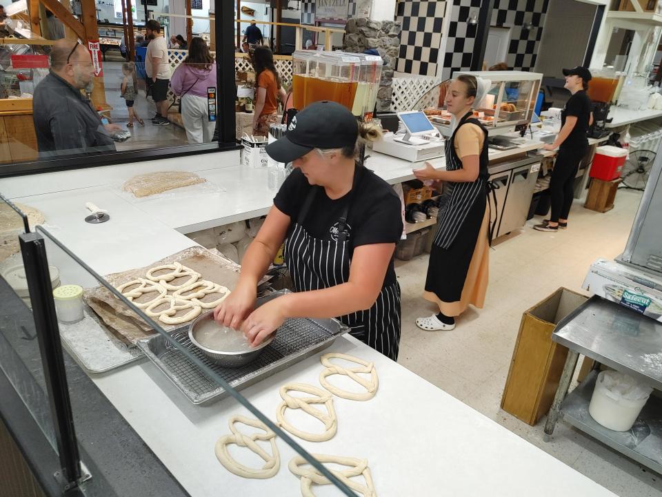 A worker rolls out pretzels at Mama's Pretzels at Jim's Farmers Market on Friday, June 9, 2023.