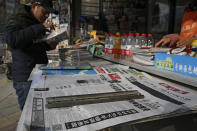 A man arranges magazines near newspapers with the headlines of China outcry against U.S. on the detention of Huawei's chief financial officer, Meng Wanzhou, at a news stand in Beijing, Monday, Dec. 10, 2018. China has summoned the U.S. ambassador to Beijing to protest Canada's detention of an executive of Chinese electronics giant Huawei at Washington's behest and demand the U.S. cancel an order for her arrest. (AP Photo/Andy Wong)