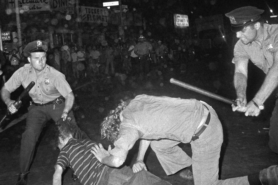 FILE - A New York City Police Department officer grabs a youth by the hair as another officer clubs a young man during a confrontation in Greenwich Village after a Gay Power march in New York, Aug. 31,1970. The start of June marks the beginning of Pride month around the U.S. and some parts of the world, celebrating the lives and experiences of LGBTQ+ communities as well as raising awareness about ongoing struggles and pushing back against efforts to roll back civil rights gains that have been made.(AP Photo/File)