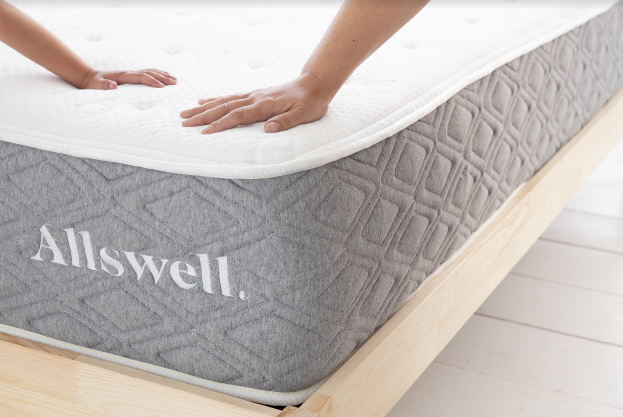 hands pushing down on the corner of an allswell luxe hybrid mattress