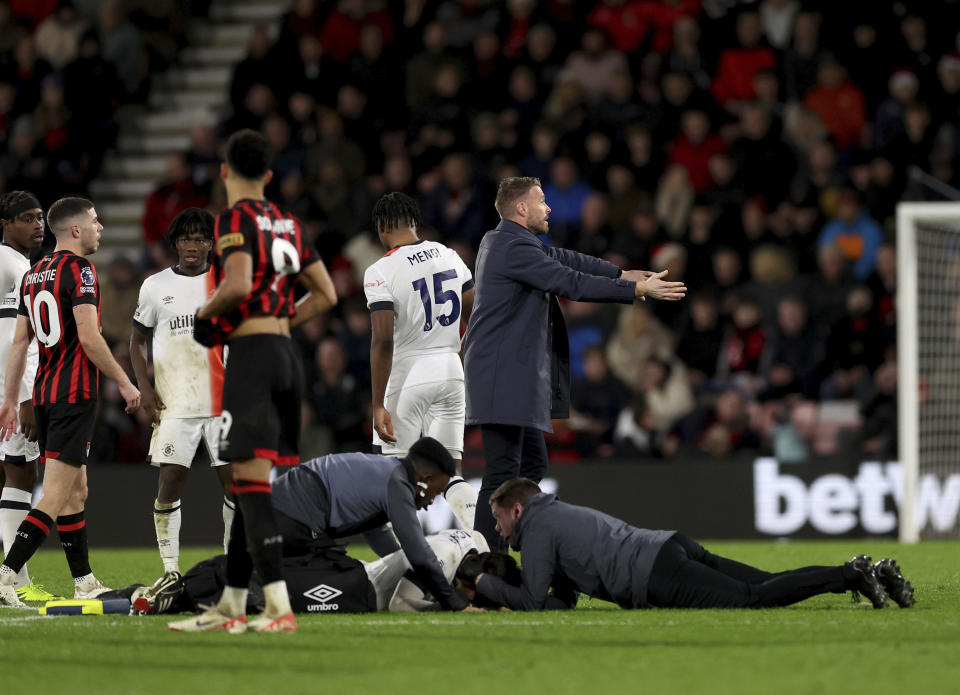 El técnico del Luton hace un gesto en la cancha mientras Tom Lockyer es auxiliado por el cuerpo médico en la cancha durante el encuentro de la Liga Premier ante el Bournemouth el sábado 16 de diciembre del 2023. (Steven Paston/PA via AP)