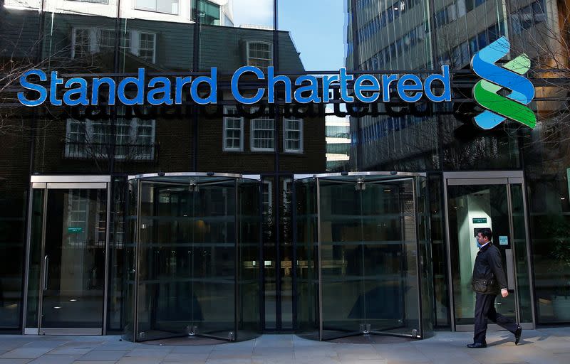 FILE PHOTO: A man walks past the head office of Standard Chartered bank in the City of London