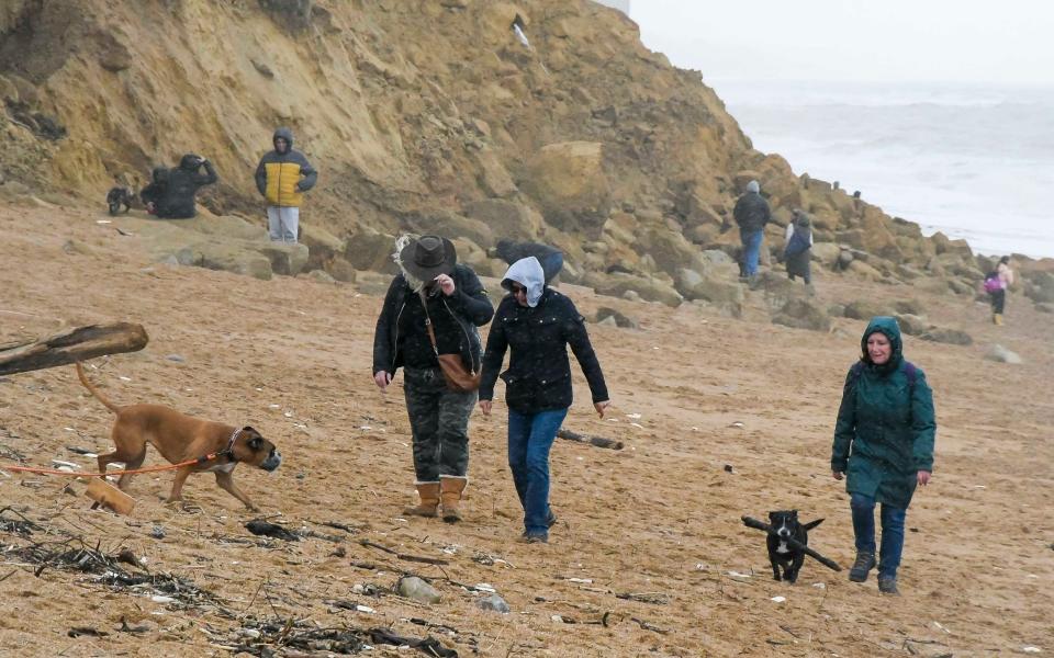 Walkers on the beach at the seaside resort of West Bay in Dorset