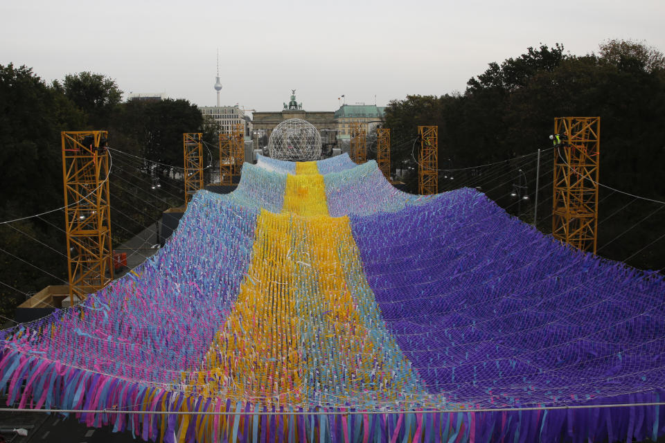 The skynet artwork 'Visions In Motion' overhangs the 'Strasse des 17. Juni' (Street of June 17) boulevard in front of the Brandenburg Gate in Berlin, Germany, Friday, Nov. 1, 2019. The art work by Patrick Shearn was made with about 100.000 streamers with written messages and is part of the celebrations marking the 30th anniversary of the fall of the Berlin Wall on Nov 9, 2019. (AP Photo/Markus Schreiber)
