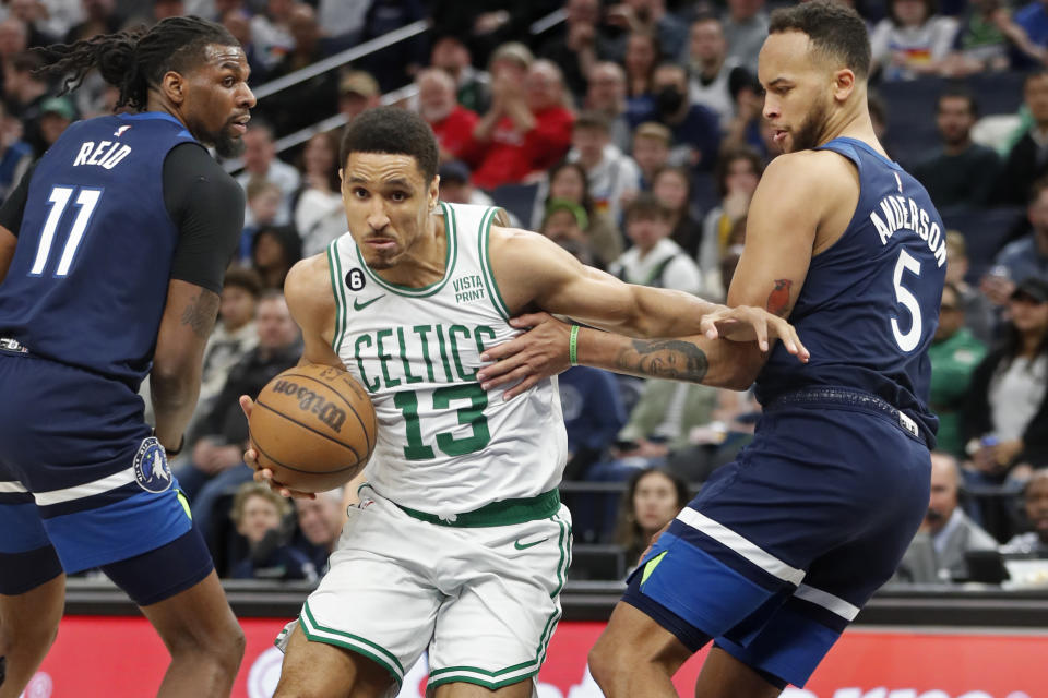 Boston Celtics guard Malcolm Brogdon, center, works his way between Minnesota Timberwolves center Naz Reid (11) and forward Kyle Anderson (5) during the fourth quarter of an NBA basketball game Wednesday, March 15, 2023, in Minneapolis. The Celtics won 104-102. (AP Photo/Bruce Kluckhohn)