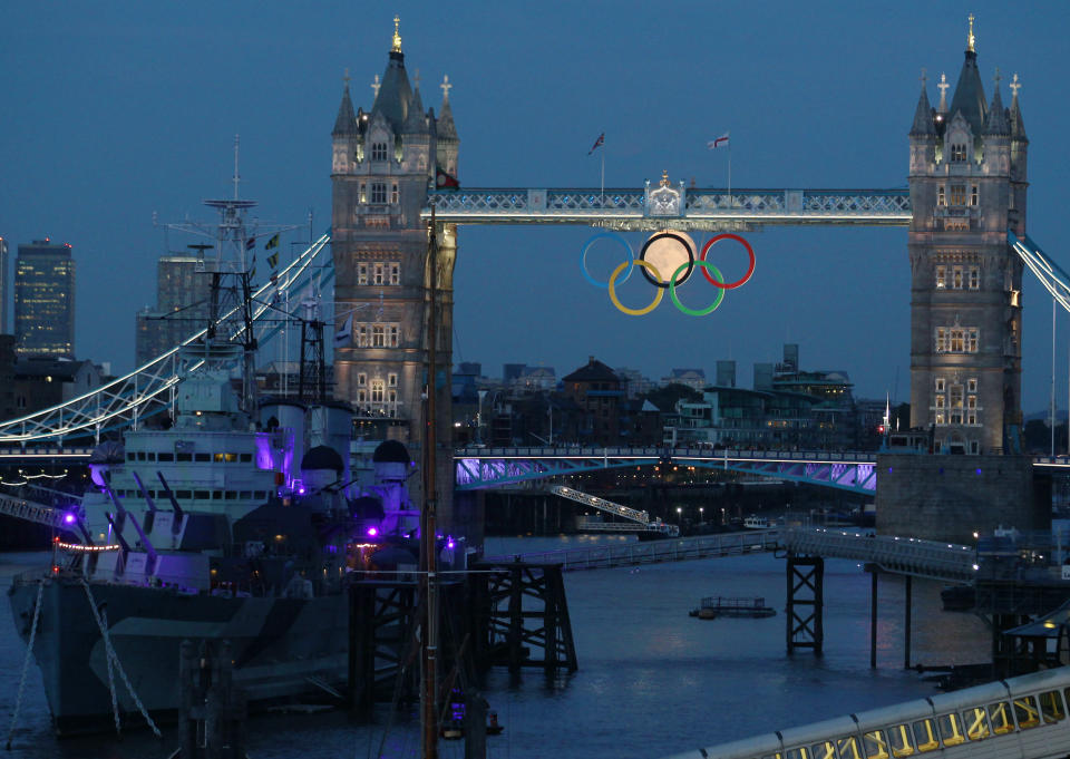 The full moon rises through the Olympic Rings hanging beneath Tower Bridge, near the HMS Belfast museum warship, during the London 2012 Olympic Games August 3, 2012. REUTERS/Luke MacGregor (BRITAIN - Tags: SPORT OLYMPICS ENVIRONMENT CITYSPACE)