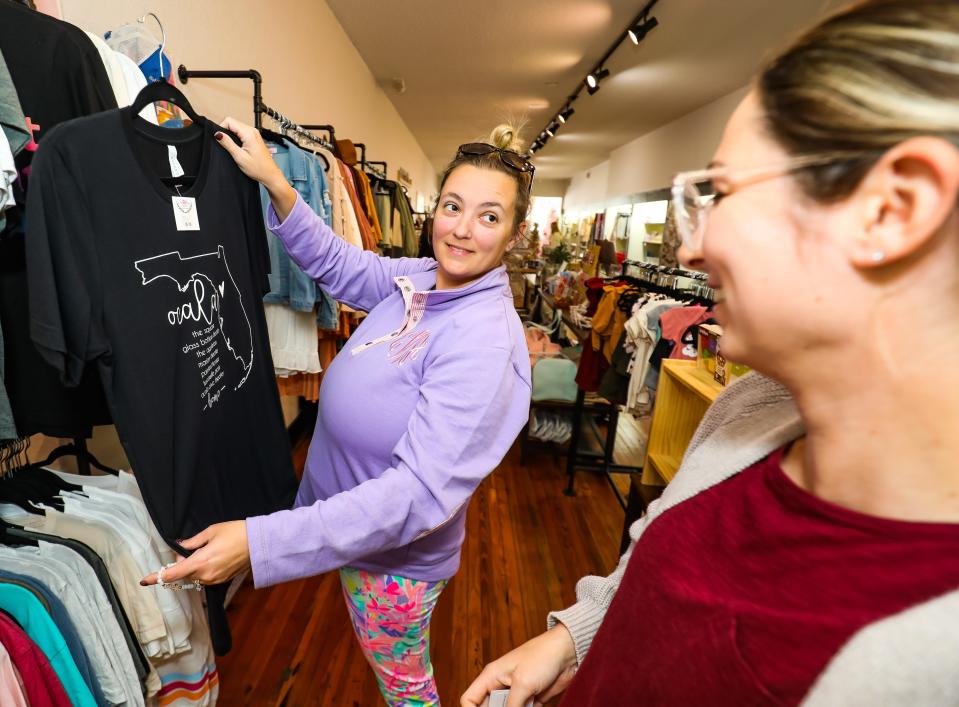 Marley Mae Market & Paperie customer Dara Wright, left, shows fellow shopper Danielle Owens, right, a t-shirt with an Ocala theme to it Wednesday afternoon, Nov. 10. The gift and stationery shop is located in downtown Ocala at 16 S. Magnolia Ave., Ocala.