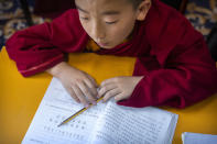 A young monk dubbed as a recognized reincarnation or "living Buddha" studies a Chinese-language textbook during a class at the Tibetan Buddhist College near Lhasa in western China's Tibet Autonomous Region, Monday, May 31, 2021, as seen during a government organized visit for foreign journalists. High-pressure tactics employed by China's ruling Communist Party appear to be finding success in separating Tibetans from their traditional Buddhist culture and the influence of the Dalai Lama. (AP Photo/Mark Schiefelbein)