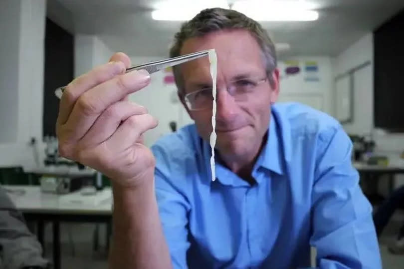 Michael Mosley holding up a piece of human tapeworm -Credit:PA