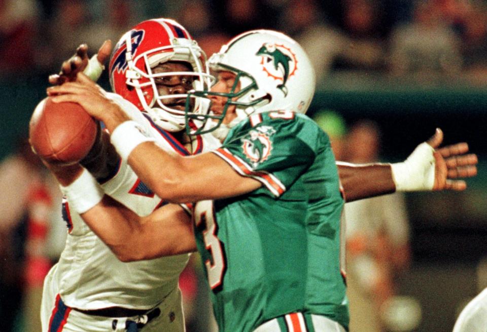 Miami Dolphins quarterback Dan Marino (R) gets sacked by Buffalo Bills defensive end Bruce Smith (L) during the first quarter at Pro Player Stadium in Miami, FL.