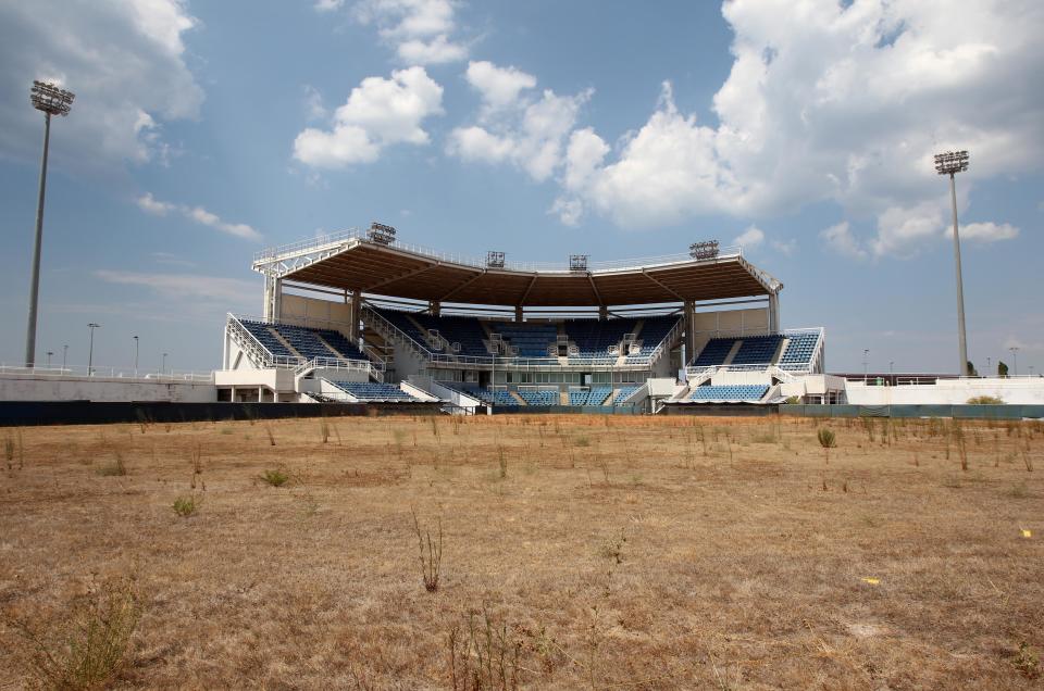 FILE - In this Thursday, Aug. 2, 2012, file photo, weeds sprout in the remains of what was once the playing field at the abandoned Olympic softball venue in southern Athens. The legacy of Athens’ Olympics has stirred vigorous debate, and Greek authorities have been widely criticized for not having a post-Games plan for the infrastructure. While some of the venues built specifically for the games have been converted for other uses, many are underused or abandoned, and very few provide the state with any revenue. Some critics even say that the multibillion dollar cost of the games played a modest role in the nation’s 2008 economic meltdown. (AP Photo/Thanassis Stavrakis)