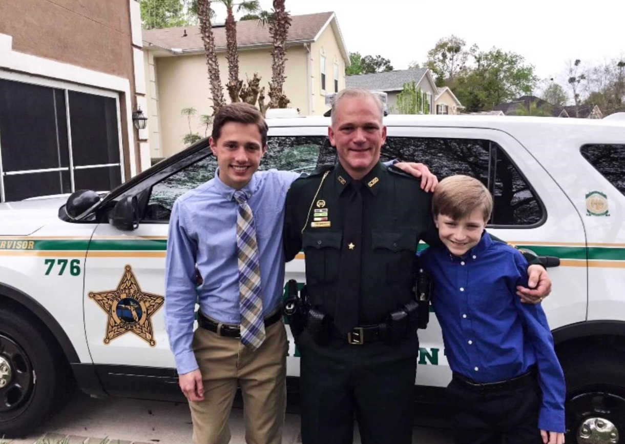 Sgt. Michael Kunovich is flanked by his sons Michael Jr., left, and Max in front of his St. Johns County Sheriff's Office vehicle.