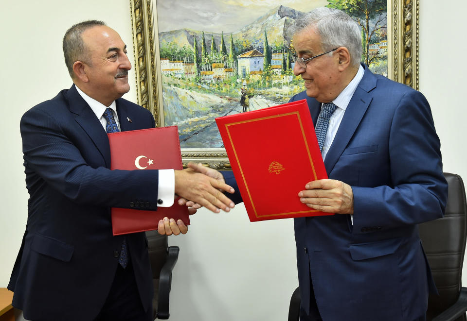 In this photo released by Lebanon's official government photographer Dalati Nohra, Turkey's Foreign Minister Mevlut Cavusoglu, left, shakes hands with his Lebanese counterpart Abdallah Bou Habib, after they sign agreements between the two countries, at the Lebanese foreign ministry, in Beirut, Lebanon, Tuesday, Nov. 16, 2021. (Dalati Nohra via AP)