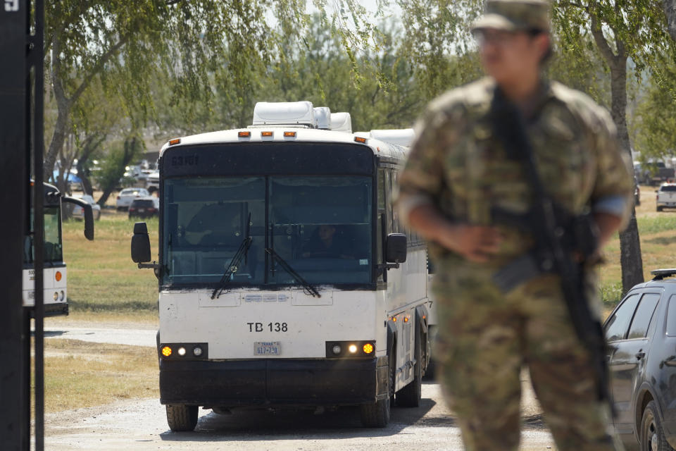 A National Guardsman stands at a gate along a border fence as a bus used to transport migrants, mostly from Haiti, departs from a makeshift camp that has developed at the International Bridge, Monday, Sept. 20, 2021, in Del Rio, Texas. The U.S. is flying Haitians camped at Texas border town back to their homeland and trying to block others from crossing the border from Mexico. (AP Photo/Eric Gay)