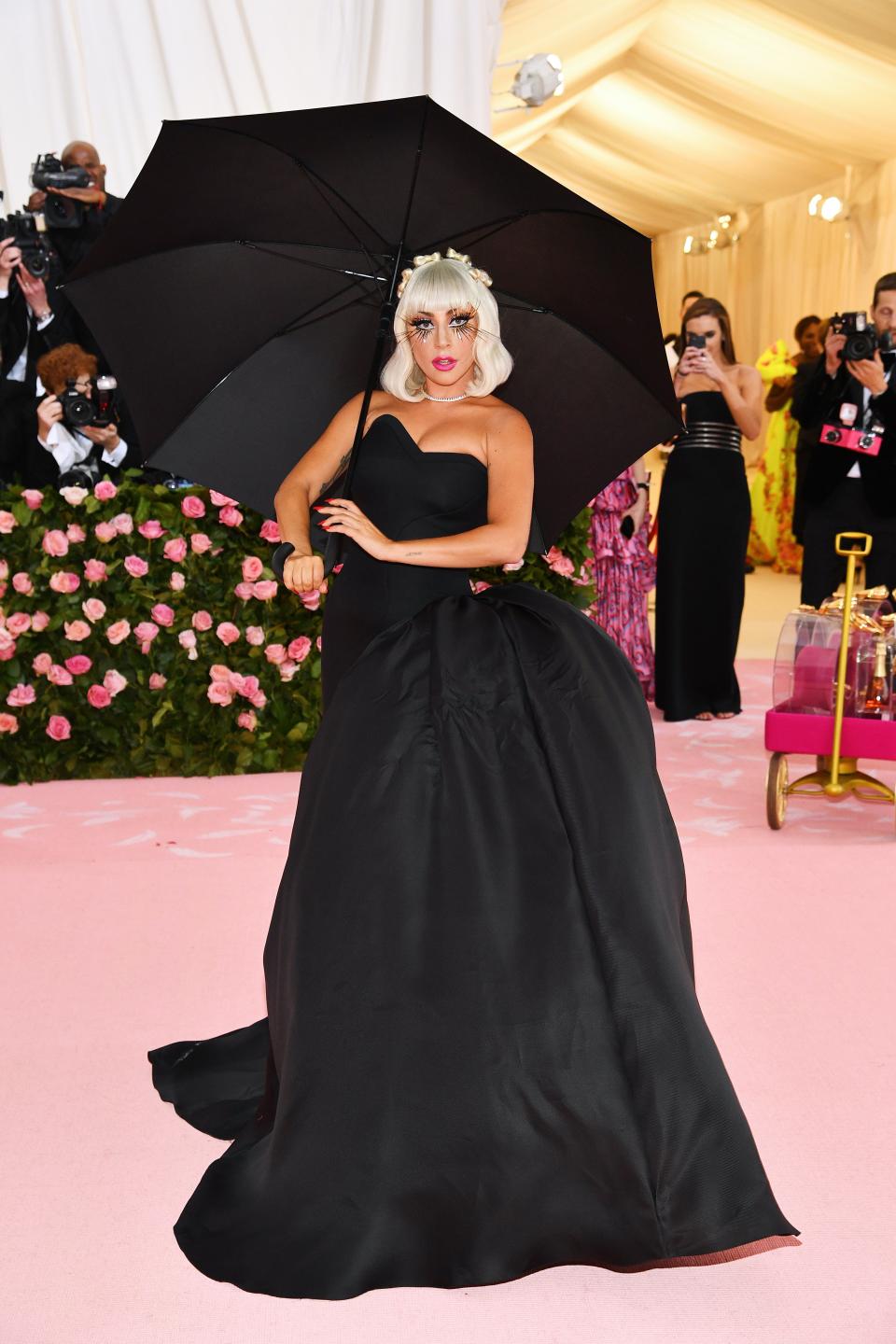 lady gaga attends the met gala in 2019 wearing black gown and carrying an umbrella
