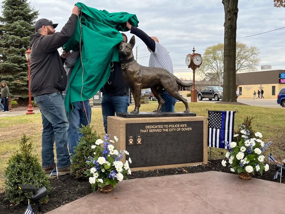 Dover cemetery department employees unveil the community's new K-9 monument during a ceremony Saturday.