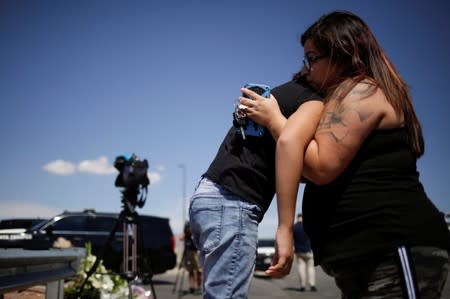 People react at the site of a mass shooting where 20 people lost their lives at a Walmart in El Paso