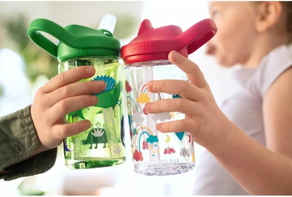 Two child models holding clear plastic water bottles with artwork adorned on them