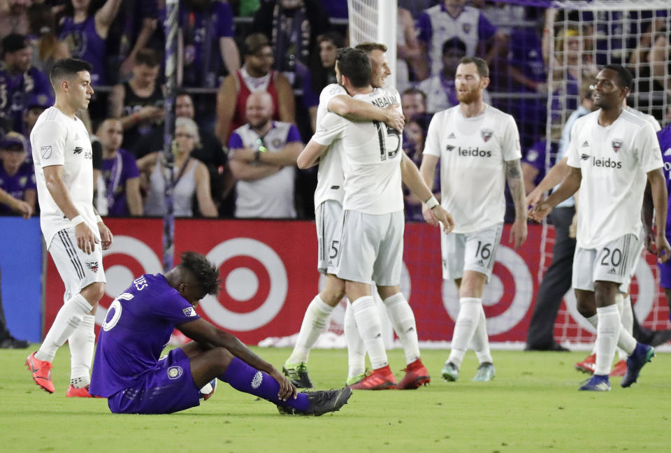 Orlando City's Carlos Ascues, second from left, sits on the field as D.C. United players, including Steve Birnbaum (15), Chris McCann (16) and Jalen Robinson (20) celebrate after defeating Orlando City in an MLS soccer match, Sunday, March 31, 2019, in Orlando, Fla. (AP Photo/John Raoux)