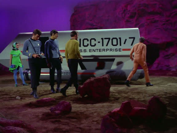 From right to left, Zefram Cochrane (Glenn Corbett), inspects Galileo as Captain Kirk (William Shatner), Mr. Spock (Leonard Nimoy), Dr. McCoy (DeForest Kelley) and Commissioner Hedford (Elinor Donahue) look on ("Metamorphosis").