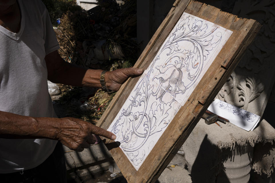 Master stone carver Tomás Ugarte shows his sketch as he works at the cemetery in the Mexico City borough of Chilmalhuacan, once the ancient village of Xochiaca, Sunday, July 2, 2023. Generations of stone carvers in Chimalhuacan, on Mexico’s City’s far east side, also created much of the stonework that adorns buildings and parks in the capital’s downtown. (AP Photo/Aurea Del Rosario)