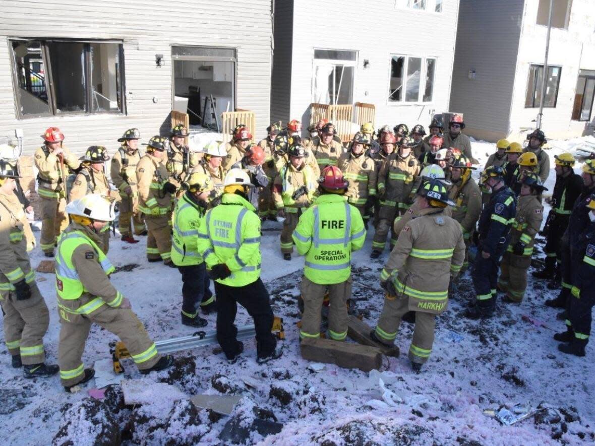 Ottawa Fire Services members huddle after rescuing two people from the rubble of the east Ottawa construction site explosion on Feb. 13, 2023. (Jean Lalonde/Ottawa Fire Services - image credit)