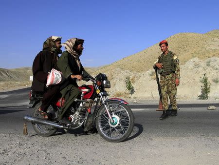 An Afghan National Army soldier (ANA) watches a motorcyclist at a checkpoint on the outskirts of Jalalabad province June 29, 2015. REUTERS/Pariwz