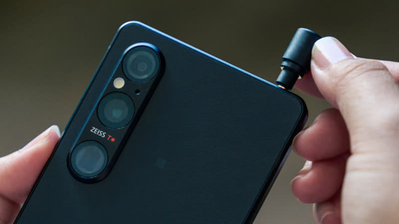  A hand pushing a headphone jack into a Sony Xperia 1 V phone. 