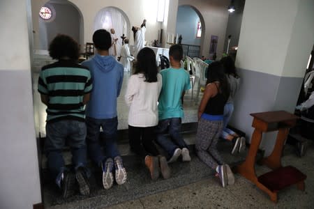 Devotees kneel while the Venezuelan priest Luis Antonio Salazar leads a Sunday Mass at Chiquinquira Catholic church in Caracas