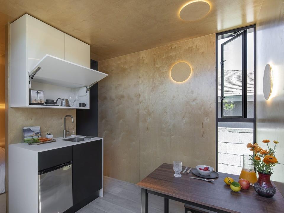 To the left you can see a kitchen set up next to the bedroom. On the right is the dining area which also doubles as a desk for working.