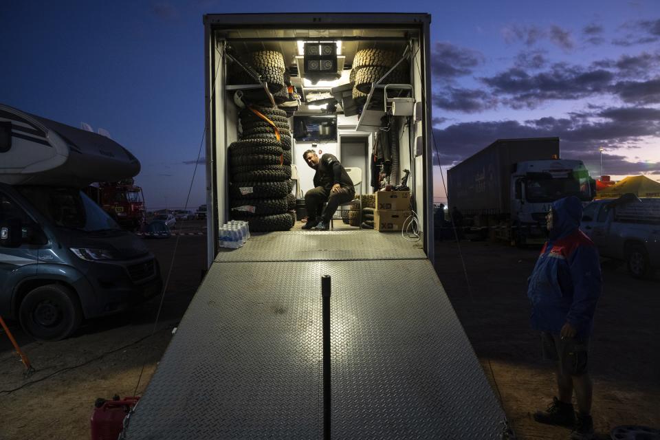 In this Thursday, Jan. 9, 2020 photo, a team staffer pauses at the bivouac after stage five of the Dakar Rally in Hail, Saudi Arabia. Formerly known as the Paris-Dakar Rally, the race was created by Thierry Sabine after he got lost in the Libyan desert in 1977. Until 2008, the rallies raced across Africa, but threats in Mauritania led organizers to cancel that year's event and move it to South America. It has now shifted to Saudi Arabia. The race started on Jan. 5 with 560 drivers and co-drivers, some on motorbikes, others in cars or in trucks. Only 41 are taking part in the Original category. (AP Photo/Bernat Armangue)