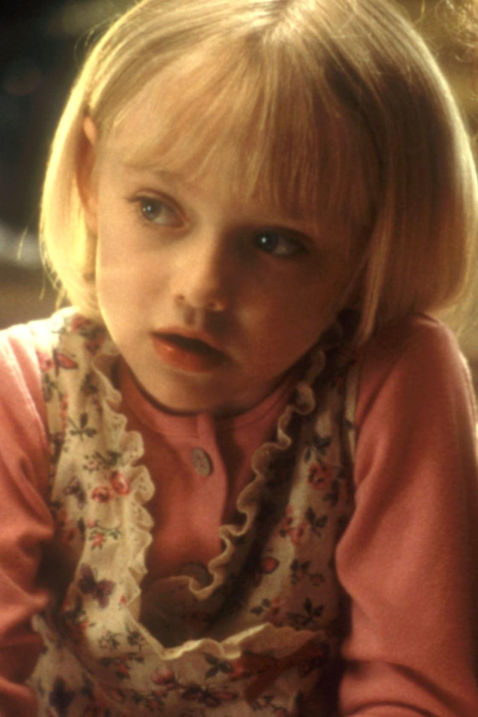 Dakota Fanning and an adult woman sit closely together as Dakota writes, showing a moment of concentration and guidance