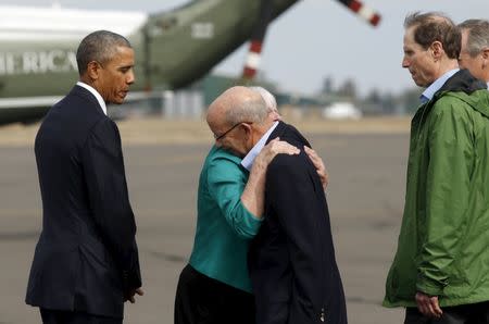 U.S. President Barack Obama watches as Eugene Mayor Kitty Piercy (2nd L) hugs Congressman Peter DeFazio (D-OR) upon arrival in Eugene, Oregon October 9, 2015. At right is Senator Ron Wyden (D-OR). Obama is traveling to nearby Umpqua Community College in Roseburg, to meet with families of the victims of last week's shooting rampage. REUTERS/Kevin Lamarque