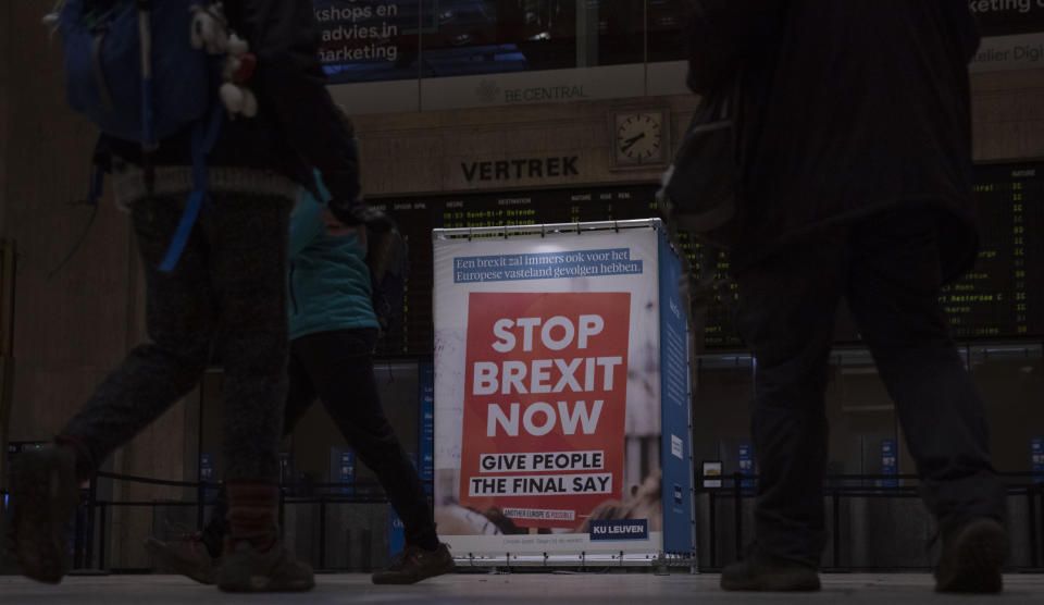 Passengers walk past a banner from the anti-Brexit campaign in Brussels, Sunday, Dec. 20, 2020. The EU and the United Kingdom were still working Sunday on a "last attempt" to clinch a post-Brexit trade deal, with EU fishing rights in British waters the most notable remaining obstacle to avoid a chaotic and costly changeover on New Year. (AP Photo/Virginia Mayo)