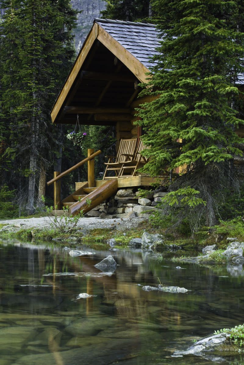 A log cabin next to a lake surrounded by trees