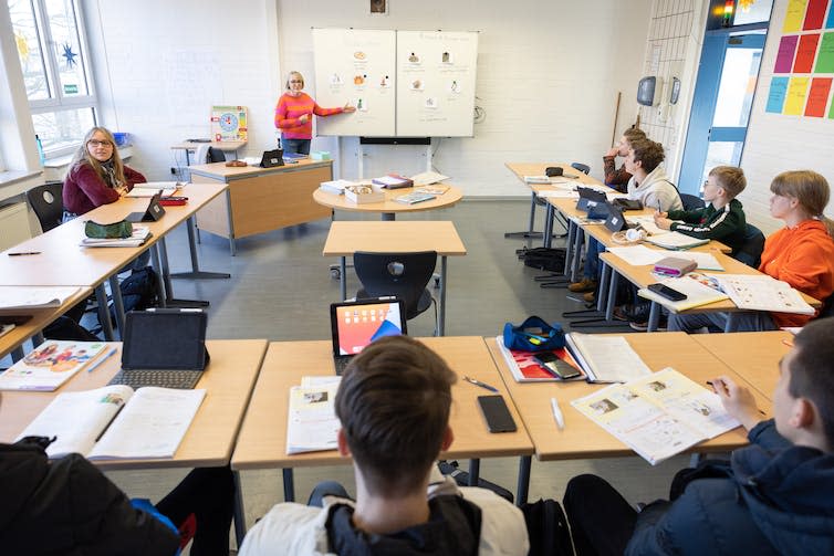 A teacher stands in front of a classroom