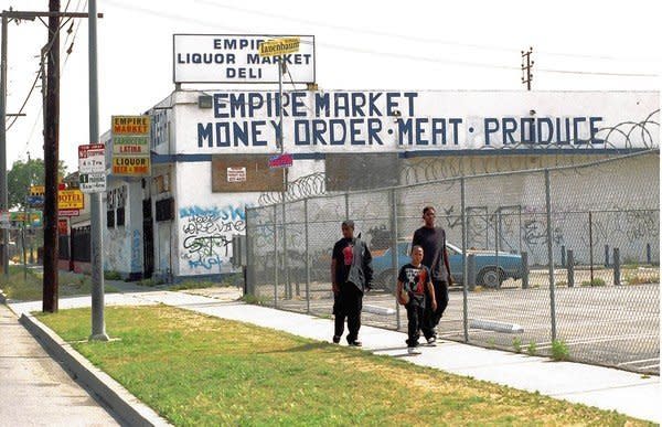 Three boys walk on the sidewalk in front of a store in Los Angeles