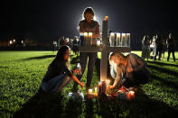 <p>Maria Reyes, Stacy Buehler and Tiffany Goldberg light candles around a cross as they attend a candlelight memorial service for the victims of the shooting at Marjory Stoneman Douglas High School that killed 17 people on Feb. 15, 2018 in Parkland, Fla. (Photo: Joe Raedle/Getty Images) </p>