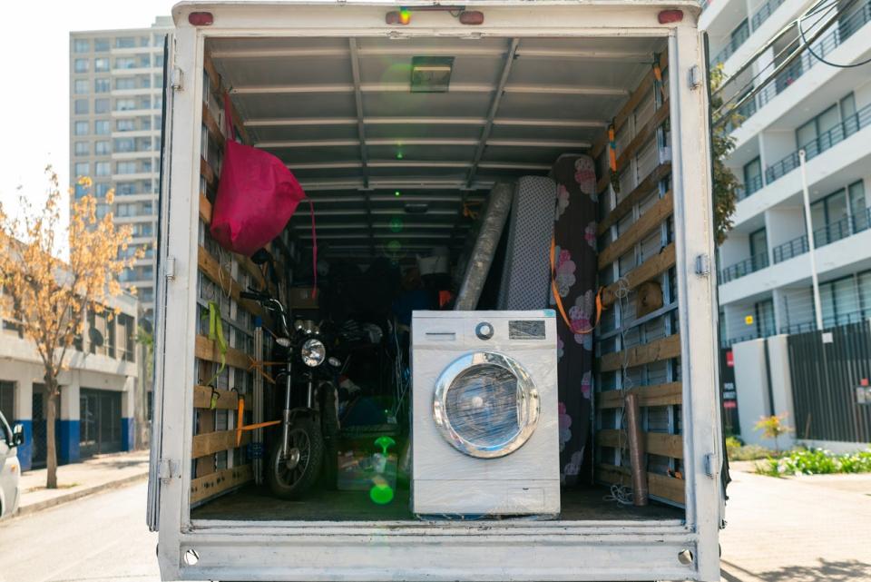 A moving truck with the back hatch open, revealing a washing machine.