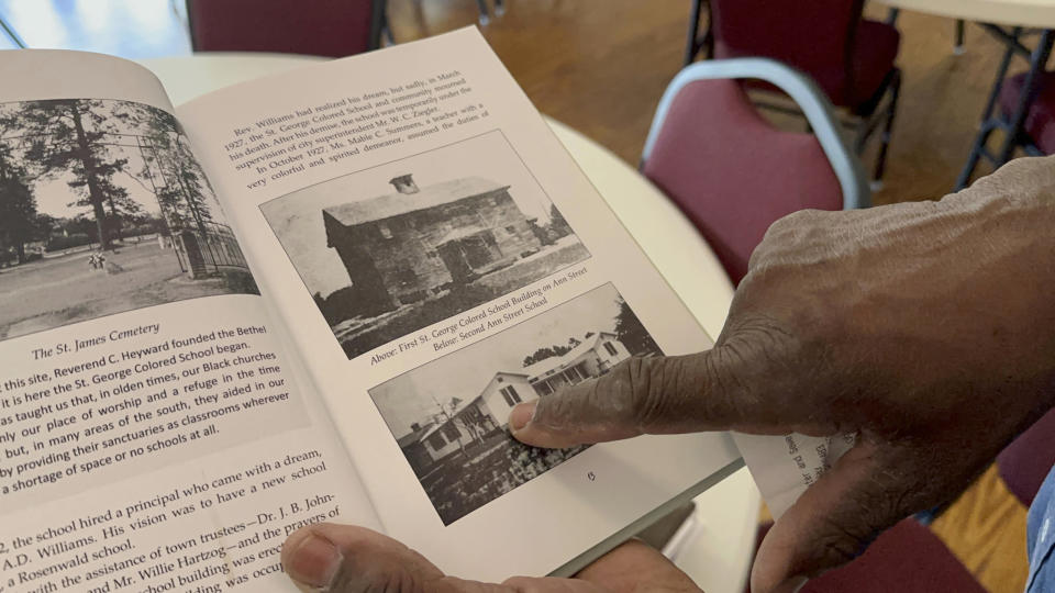 Ralph James points to an old photo of the Rosenwald School he has helped restore in St. George, S.C., on Tuesday, July 11, 2023. Jewish businessman Julius Rosenwald donated money to help build 5,000 schools for Black students across the American South a century ago. Only about 500 are standing and roughly half of them have been restored. (AP Photo/Jeffrey Collins)