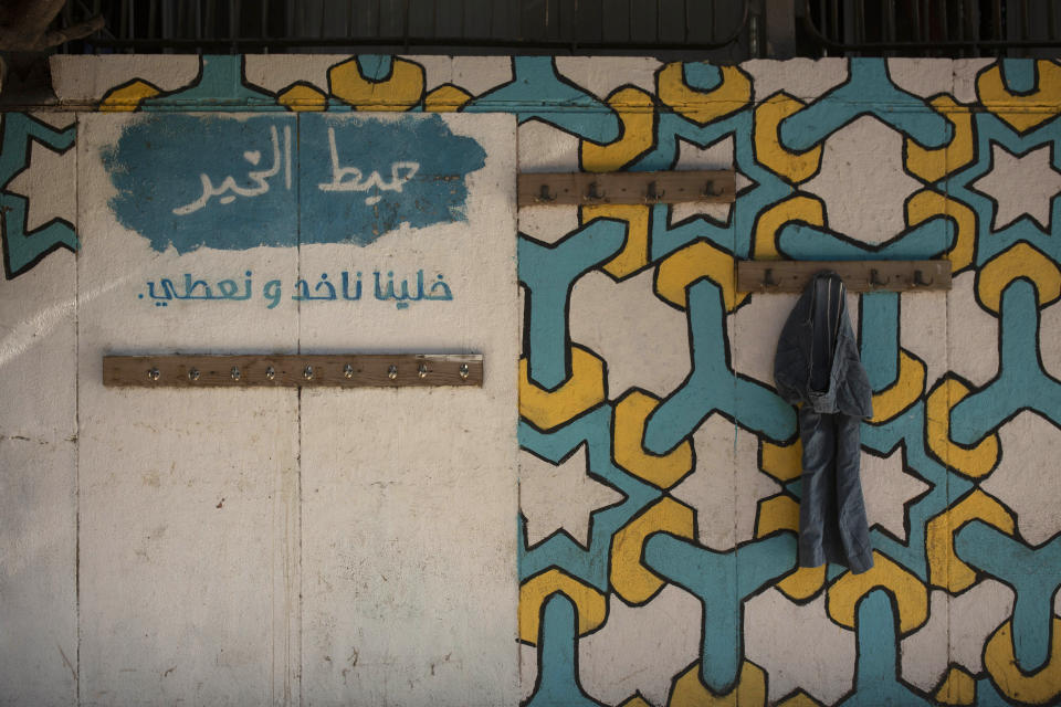 In this Monday, Dec. 23, 2019, photo, a lone pair of trousers hangs on the "Wall of Kindness," where people can leave clothes or other items for anyone in need, in Beirut, Lebanon. Lebanon is entering its third month of protests, the economic pinch is hurting everyone, and the government is paralyzed. So people are resorting to what they've done in previous crises: They rely on each other, not the state. Arabic reads: "Let us give and take." (AP Photo/Maya Alleruzzo)