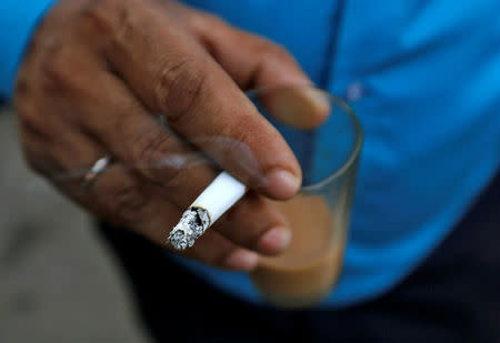 A man smokes a cigarette along a road in Mumbai, India, October 26, 2016. REUTERS/Danish Siddiqui/File Photo
