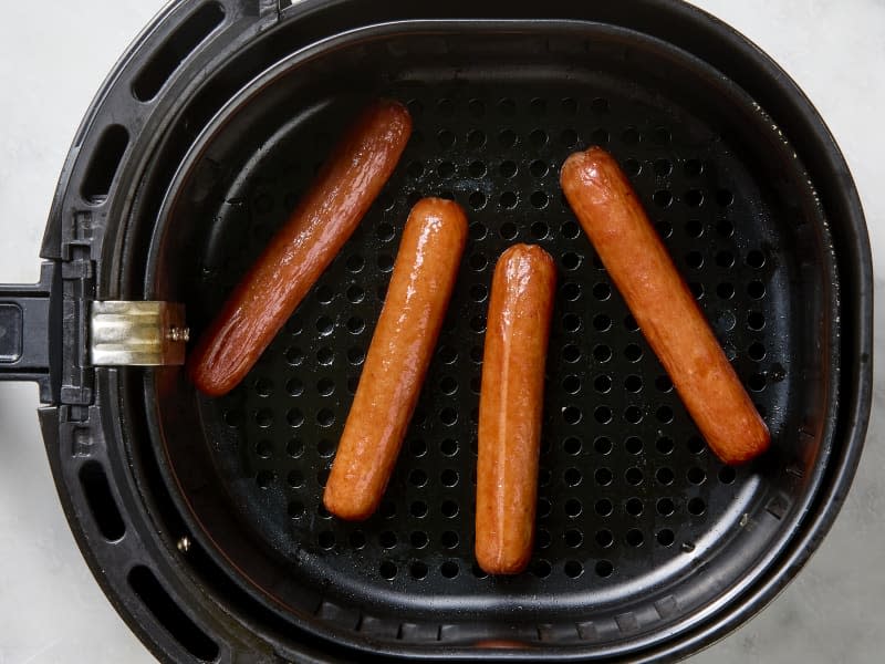 overhead photo of cooked hot dogs in an air fryer basket