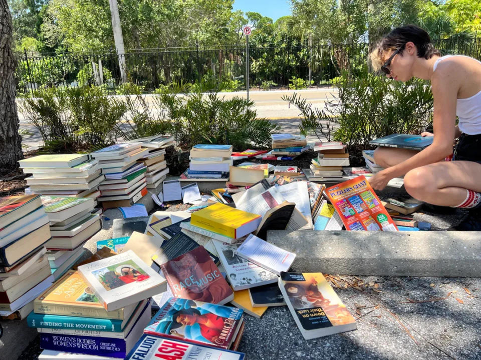 A student goes through books on the New College campus on their way to the dump. A bin overflowed last week with books from the library and the now-defunct Gender and Diversity Center