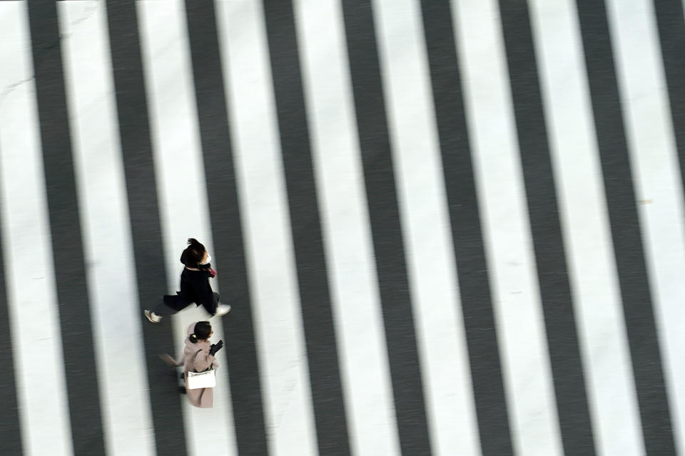 People wearing protective masks to help curb the spread of the coronavirus run along a pedestrian crossing Thursday, Feb. 25, 2021, in Tokyo. The Japanese capital confirmed more than 340 new coronavirus cases on Thursday. (AP Photo/Eugene Hoshiko)