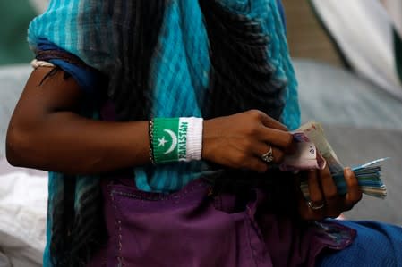 A woman counts cash as she sells patriotic memorabilia, ahead of Pakistan's Independence Day, along a market in Karachi