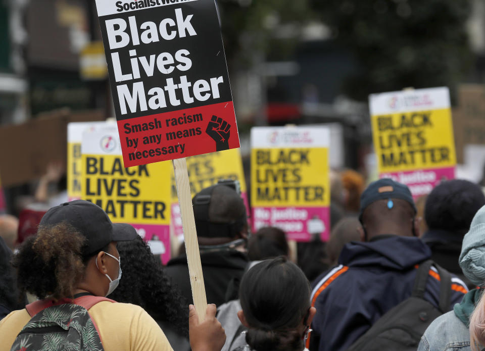 FILE - In this file photo dated Sunday, Aug. 30, 2020, Black Lives Matter protesters hold posters as they march through Notting Hill during the "Million People March" through central London. A government inquiry, by a panel of experts, has concluded Wednesday March 31, 2021, that there is racism in Britain, but it’s not a systematically racist country that is “rigged” against non-white people, although many ethnic-minority Britons greeted that claim with skepticism. (AP Photo/Frank Augstein, FILE)